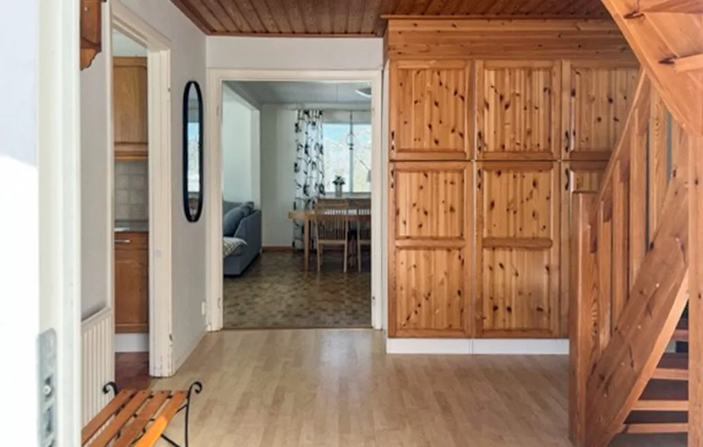 Un pasillo revestido de madera da a una zona de estar y comedor.