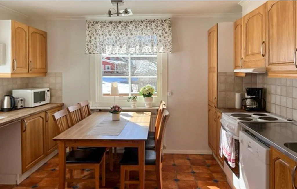 Una cocina y comedor con gabinetes de madera, una mesa y una ventana.