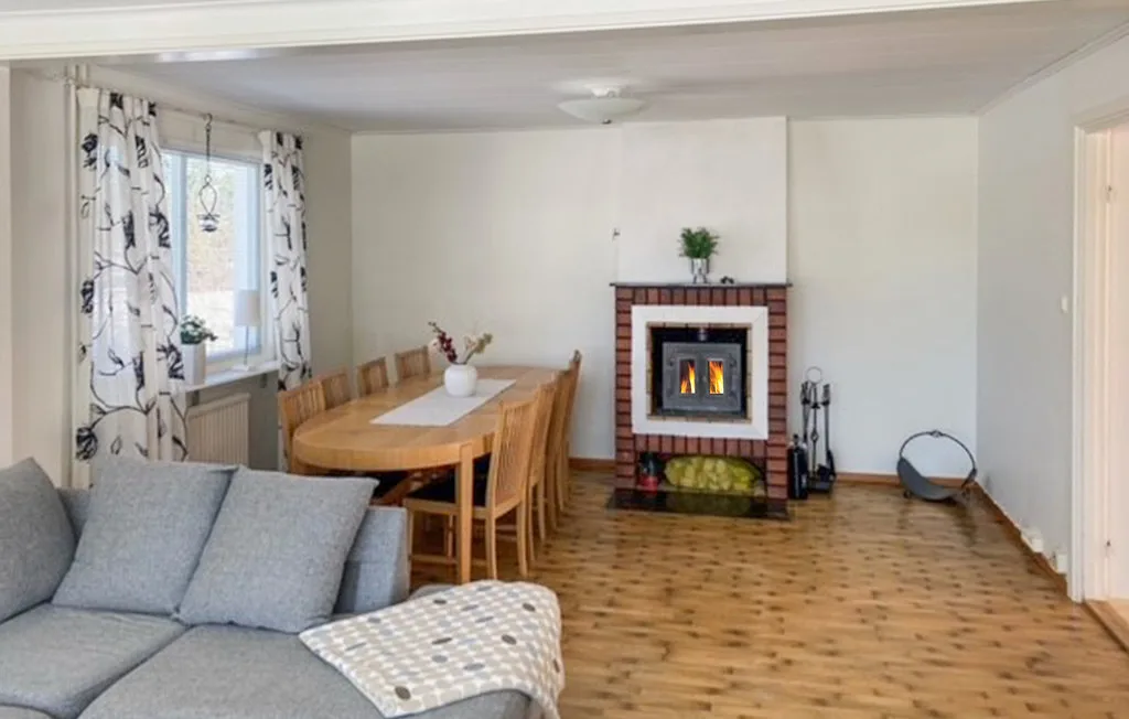Una sala de estar y comedor con asientos, una mesa de madera y una chimenea encendida.