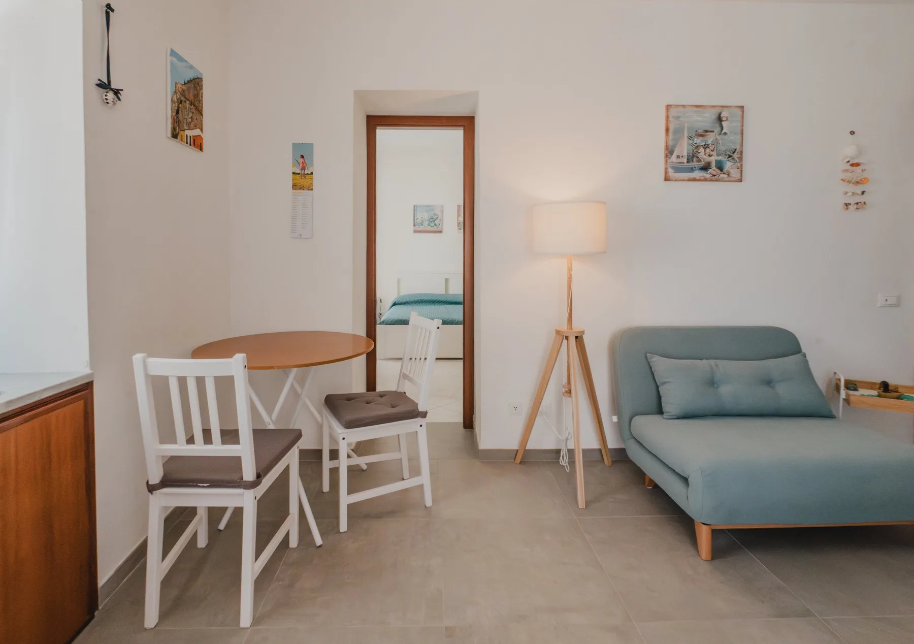 A bright sitting room with a blue sofa, table, chairs, and floor lamp.