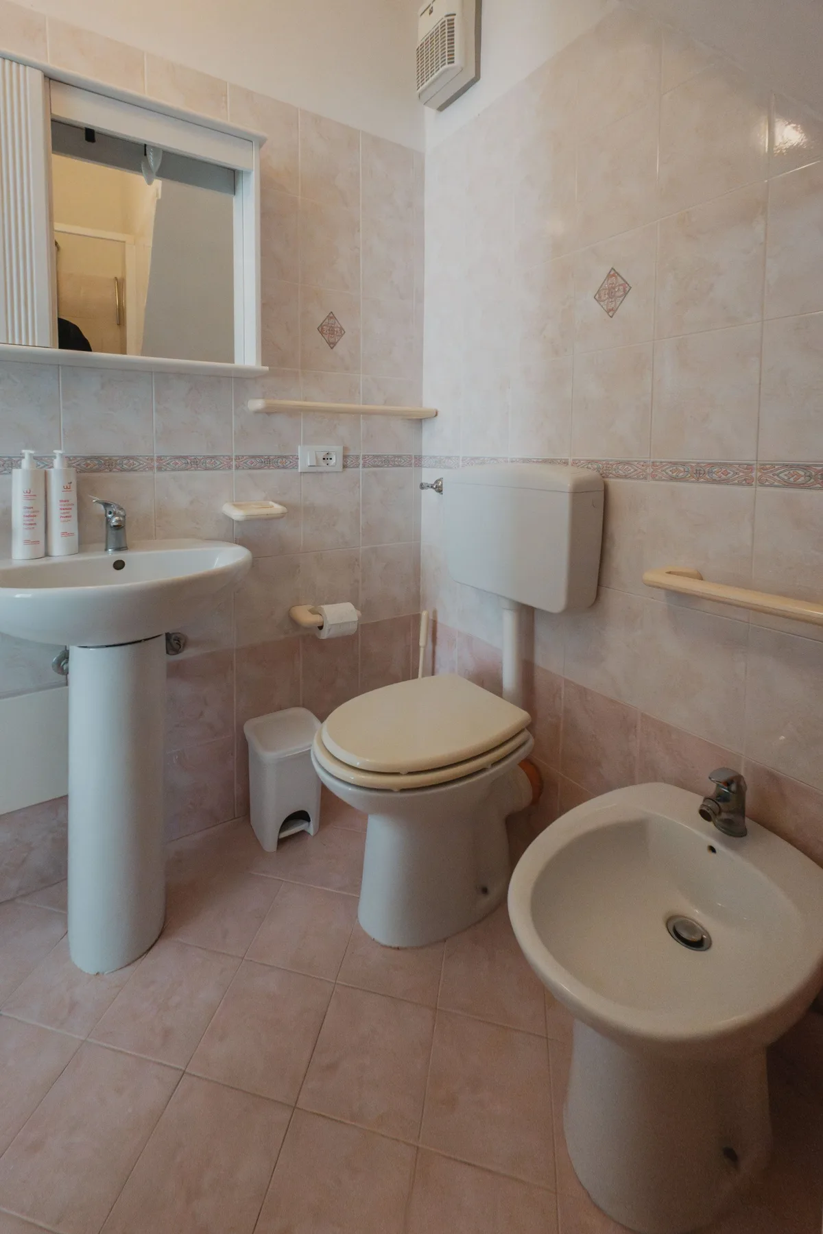 A tiled bathroom with a sink, toilet, and bidet.