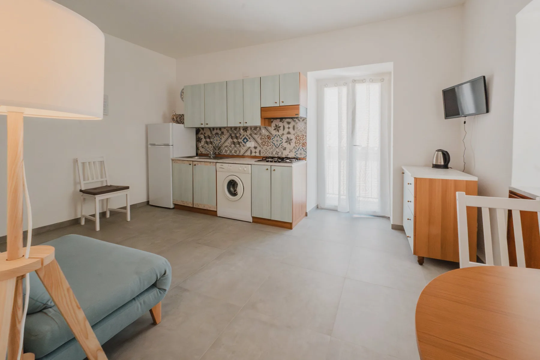 A compact kitchen and dining area with a washing machine and seating.