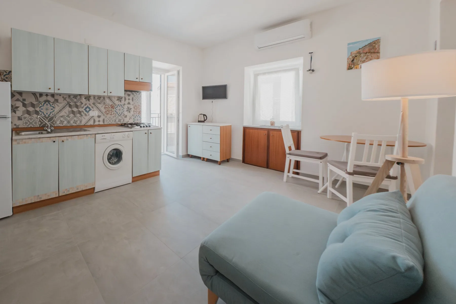 A bright open-plan living area with a kitchen, dining table, and seating.