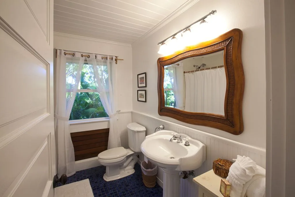 A bathroom with a pedestal sink beneath a large framed mirror.