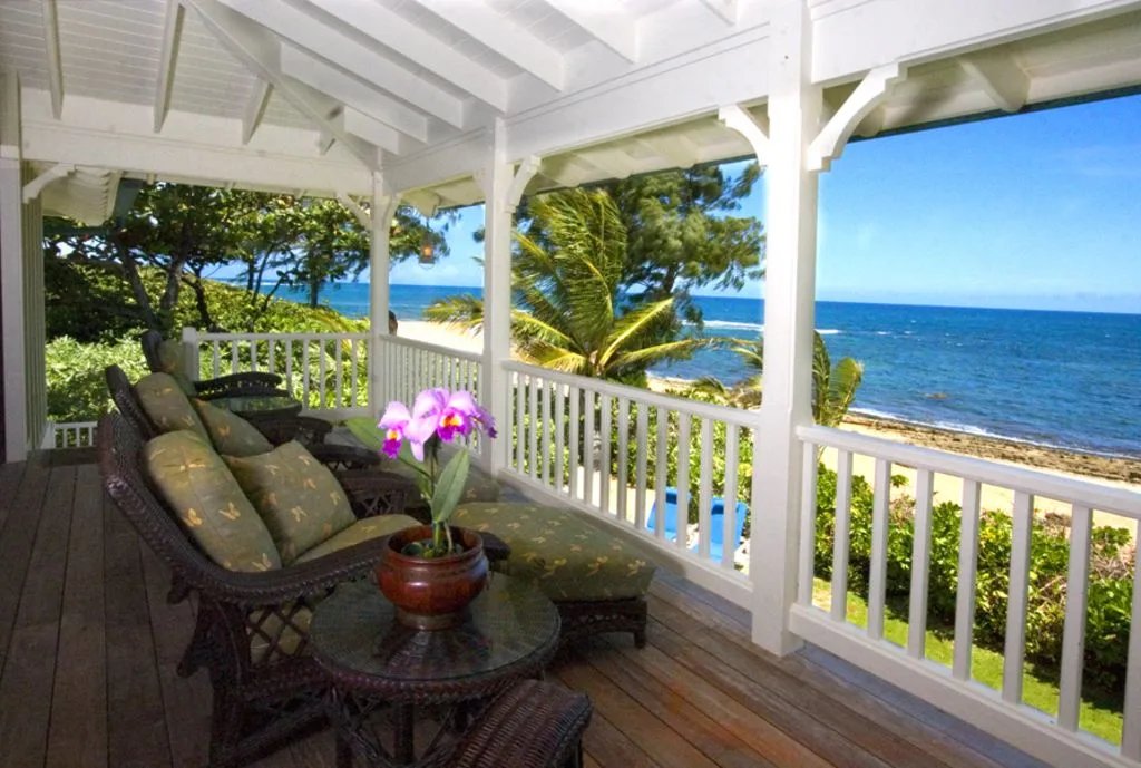 A covered veranda with cushioned seating overlooks the ocean.