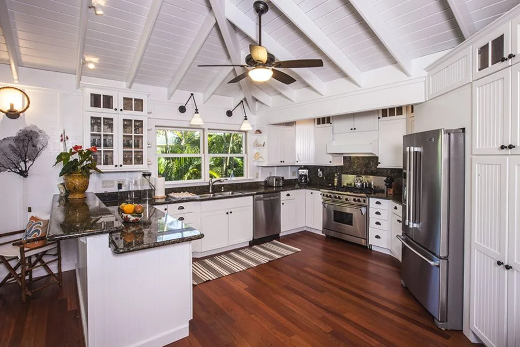 A bright kitchen with white cabinets, dark countertops, and a central island.