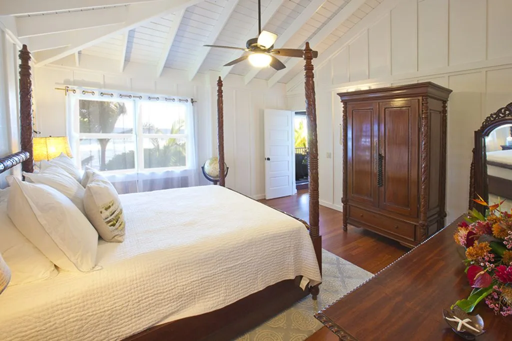 A bright bedroom with a large bed beneath a sloped white ceiling.