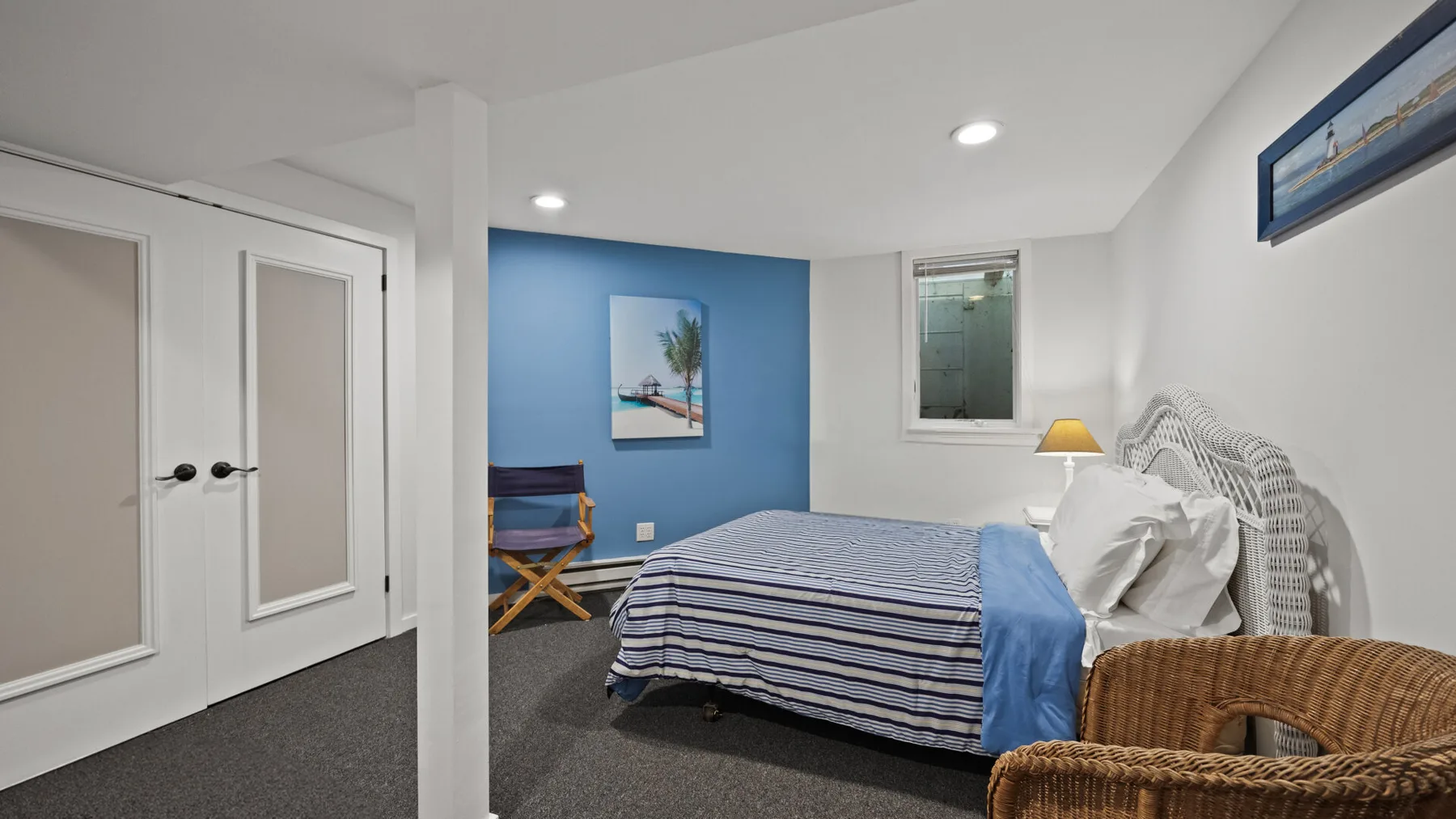 Un dormitorio con una cama a rayas, una pared azul y puertas blancas de armario.