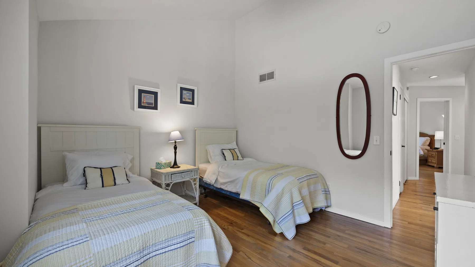 Un dormitorio con dos camas, ropa de cama a rayas y una mesita de noche.