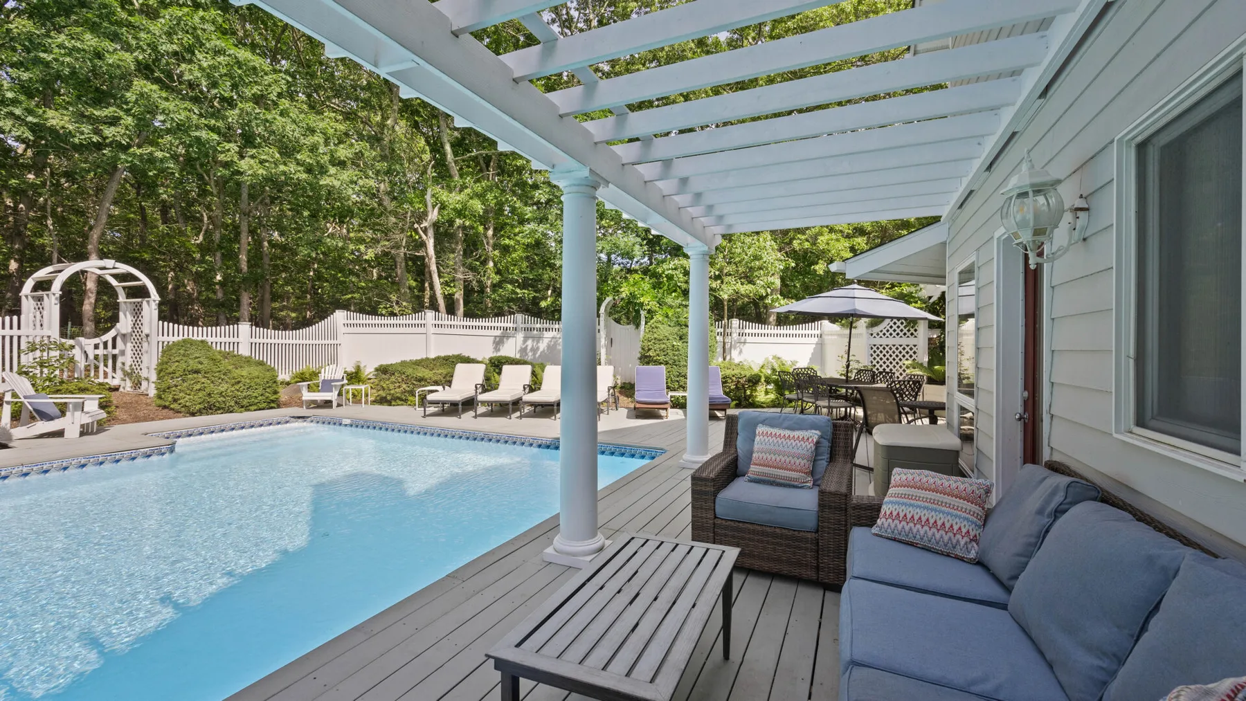 Un patio cubierto junto a la piscina con asientos al aire libre.