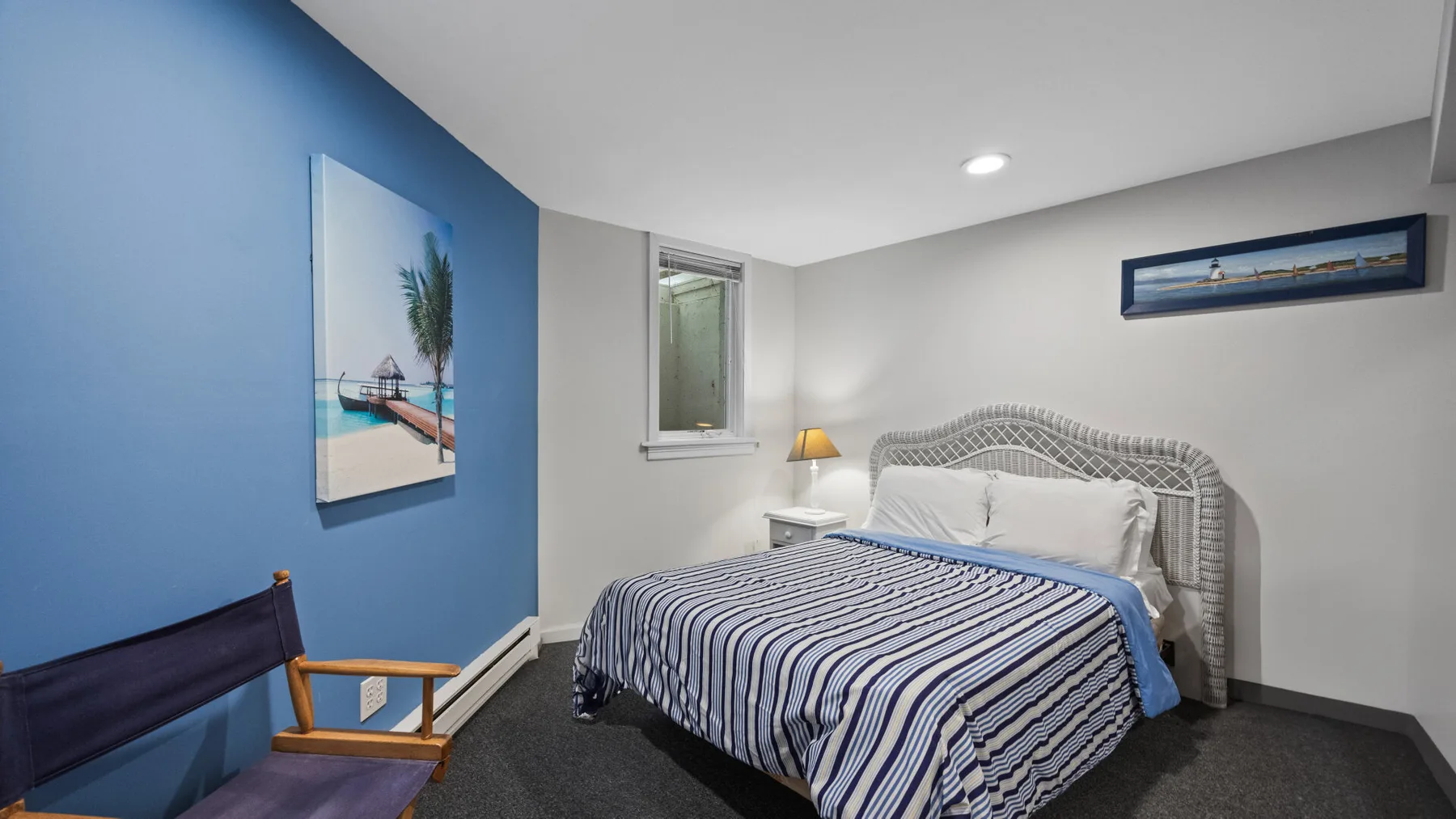 Un dormitorio con una cama, ropa de cama a rayas y una pared azul.