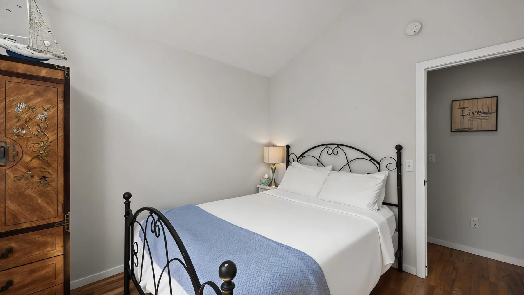 Un dormitorio con una cama tendida y una manta azul.