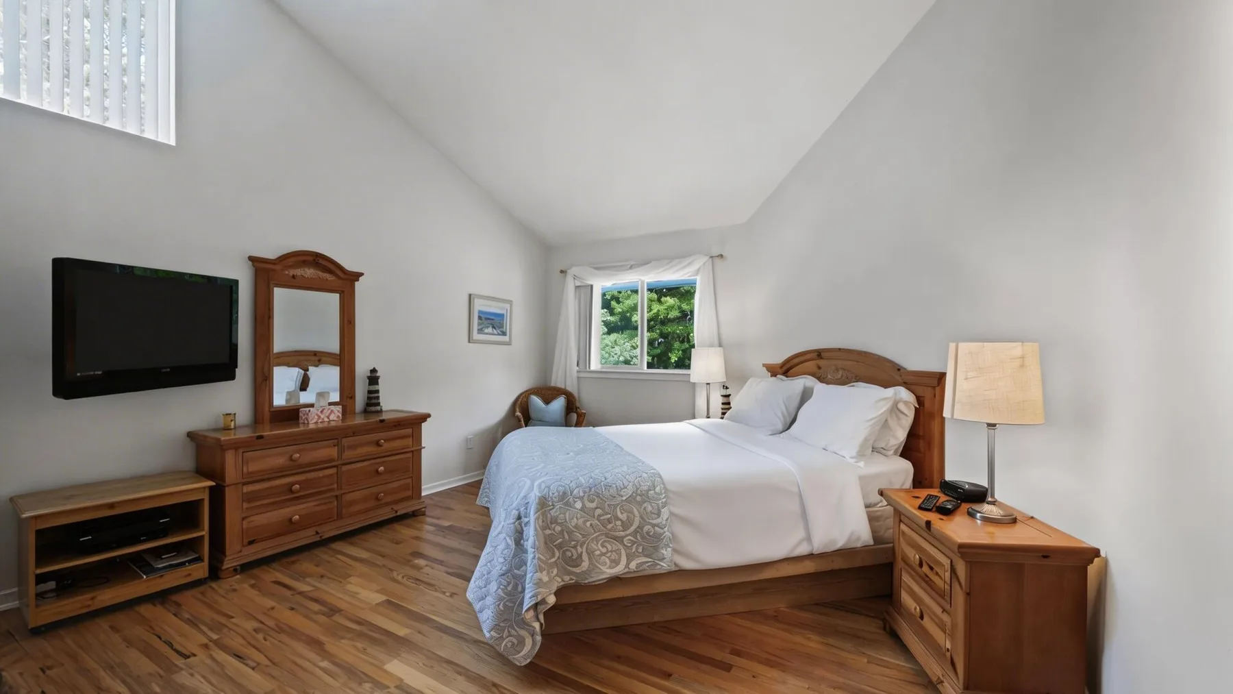 Un dormitorio luminoso con cama de madera, cómoda y ventana.