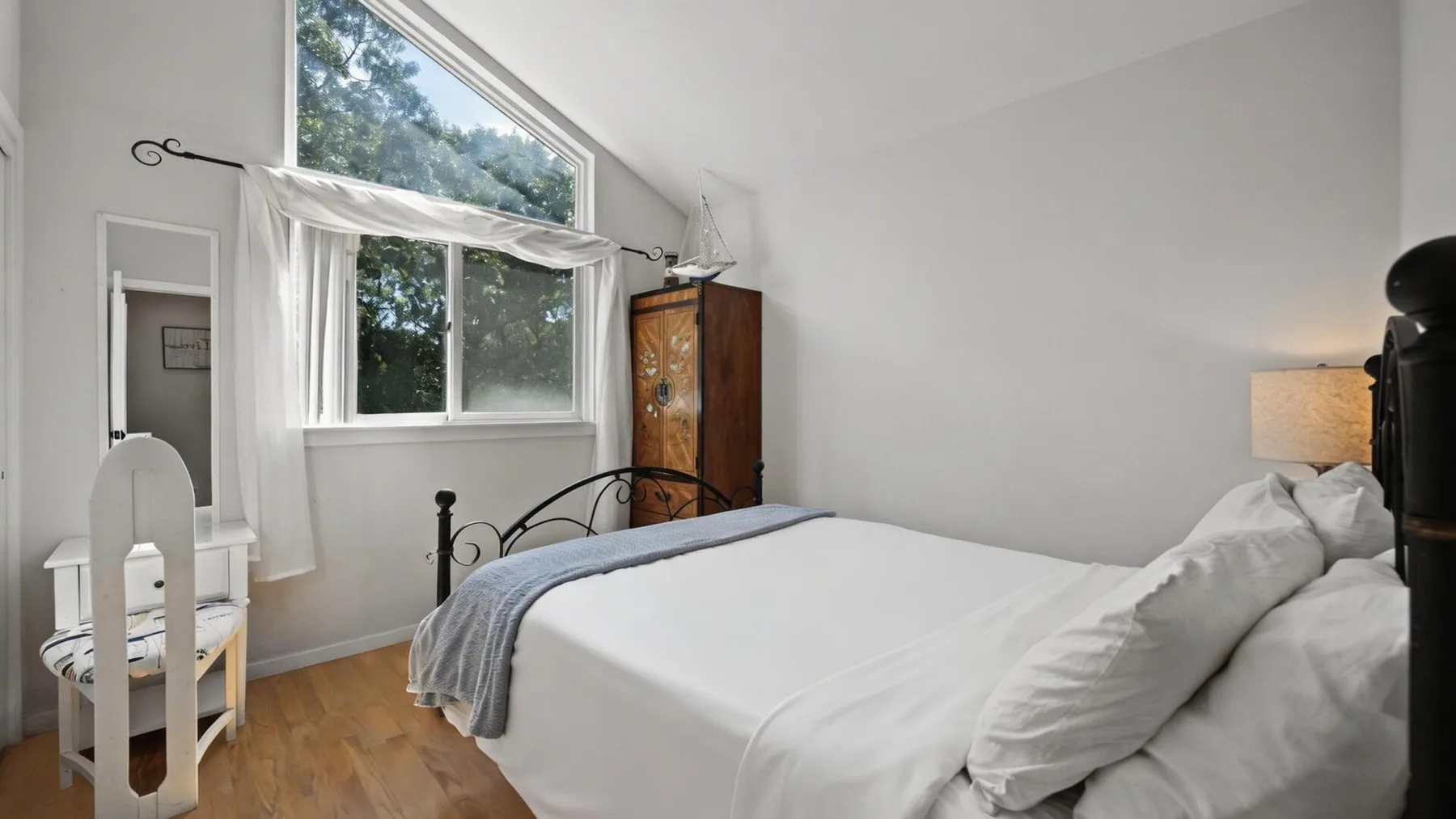 Un dormitorio luminoso con una cama junto a una ventana grande.