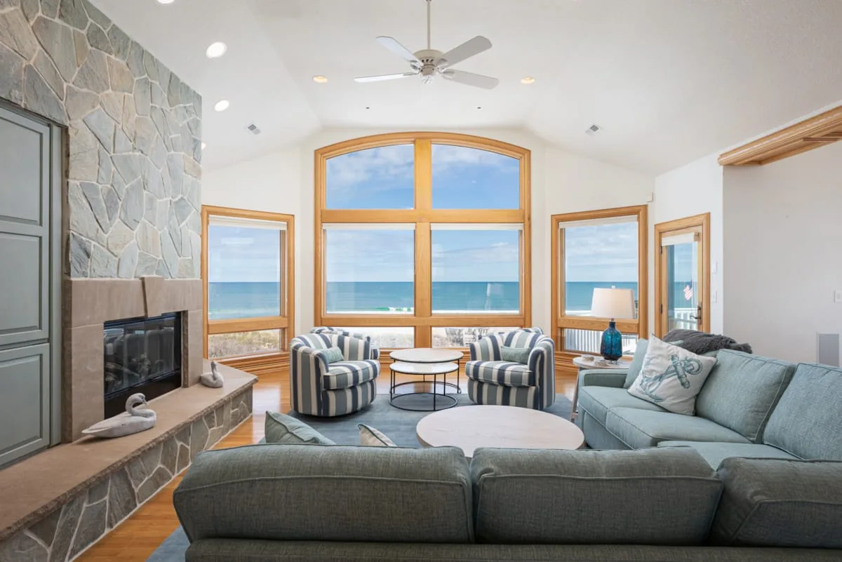 A bright living room with a sectional seating area and large ocean-facing windows.