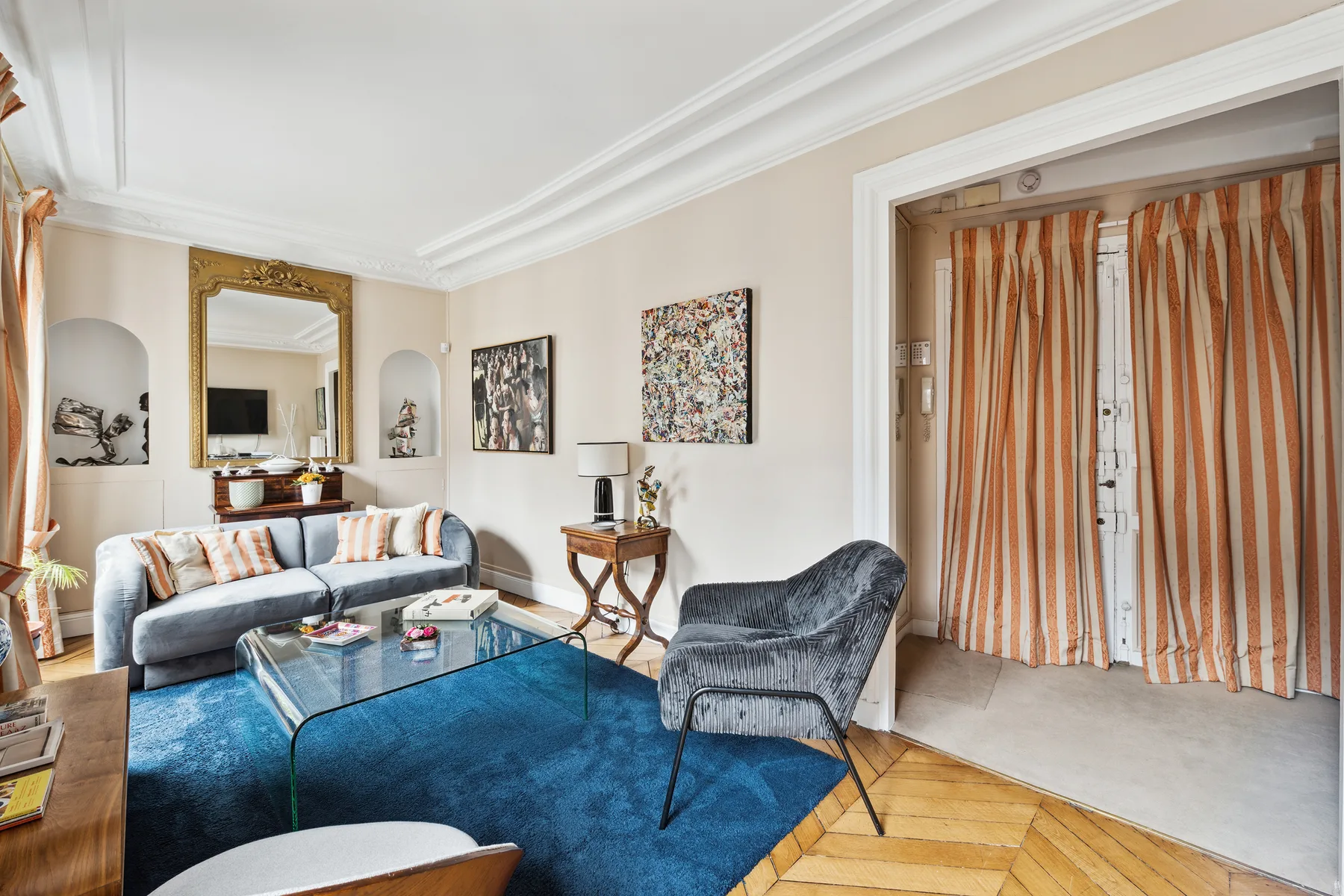A living room with seating around a glass coffee table on a blue rug.