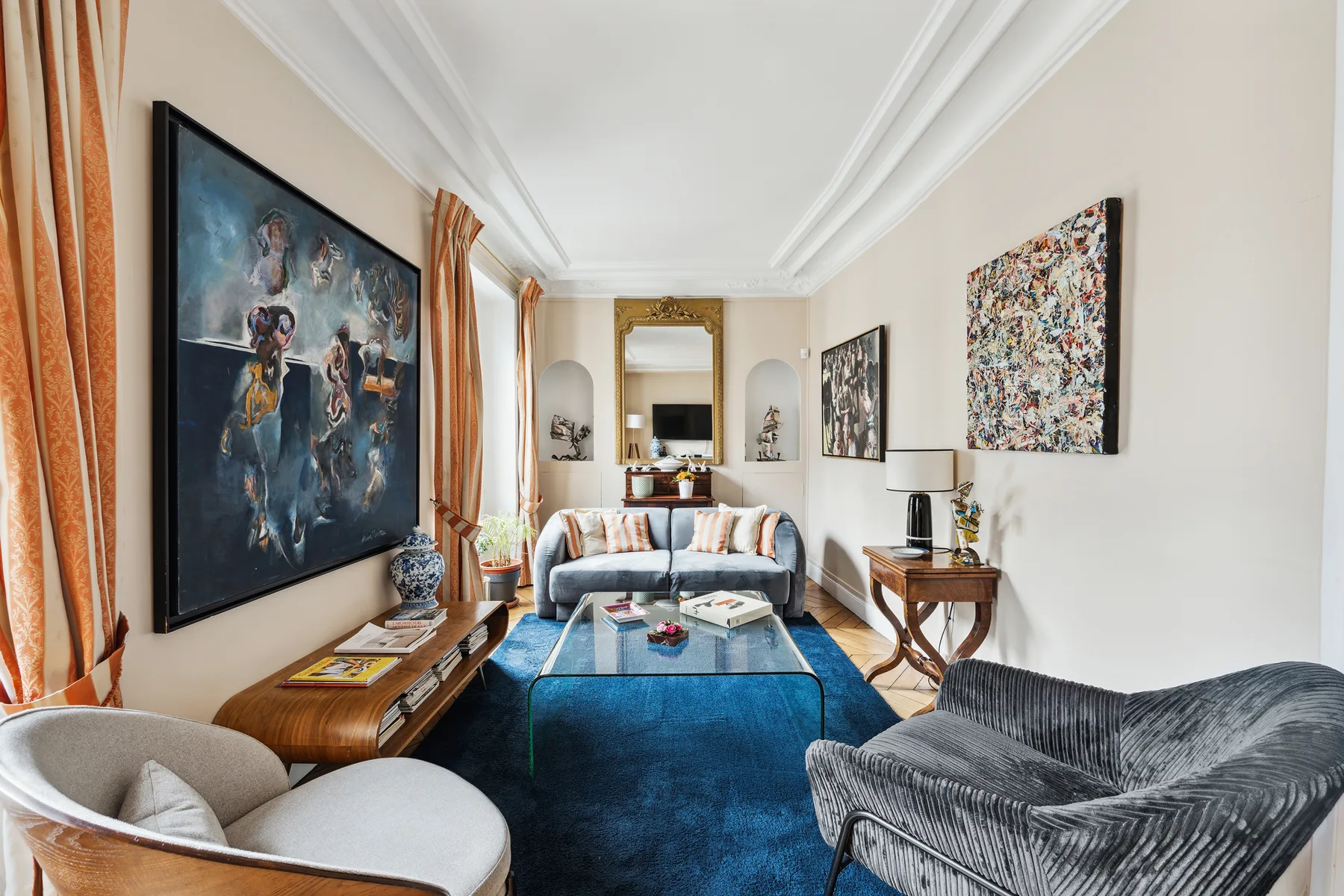 A bright living room with a blue rug, seating, and framed artwork.