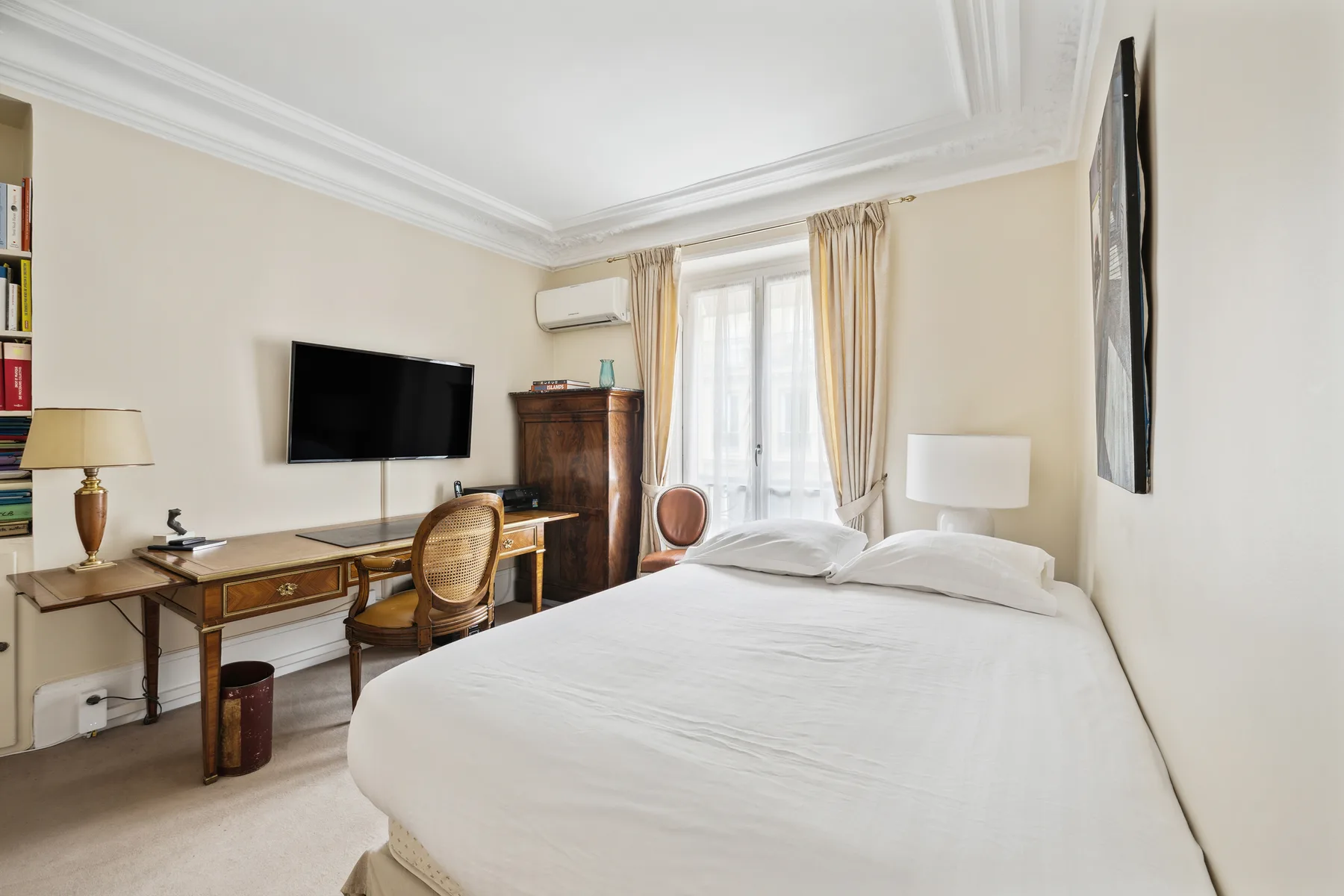 A bright bedroom with a neatly made bed and a desk beside the window.