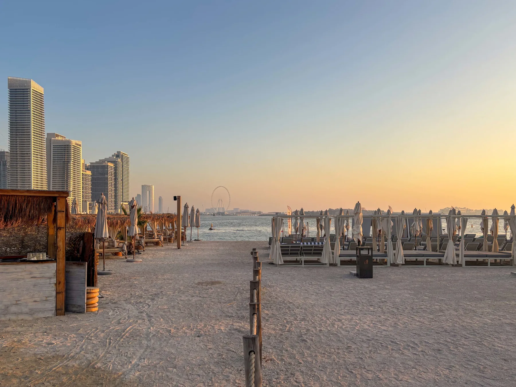Un paseo marítimo de arena con asientos y edificios altos a lo lejos.