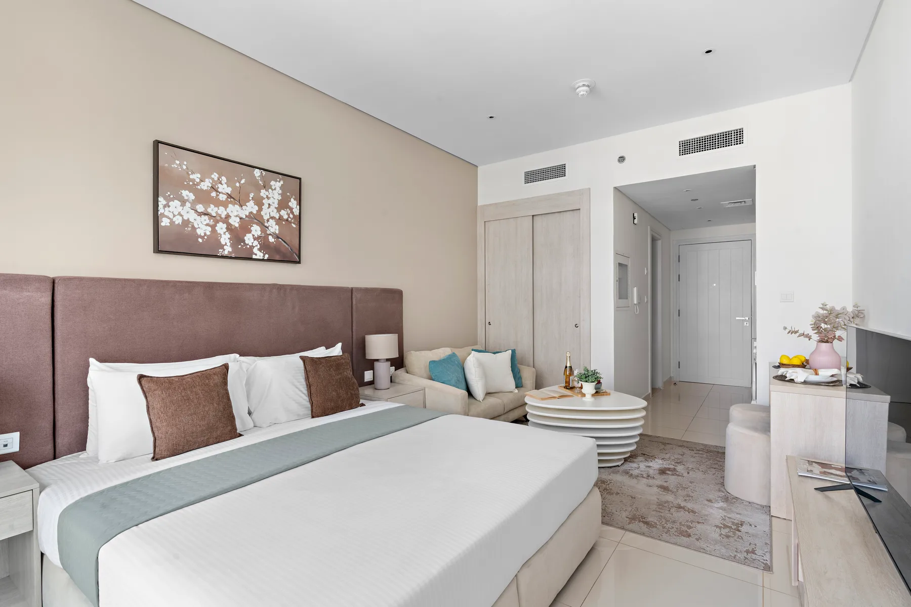 A bedroom with a large bed, bedside tables, and a round coffee table.