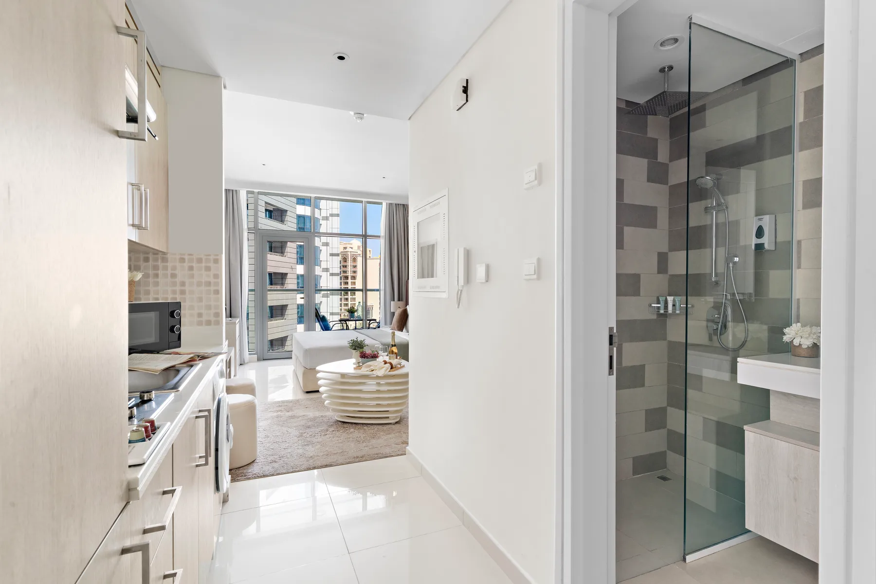Una cocina y sala de estar diáfanas y luminosas dan a un baño con ducha de vidrio.