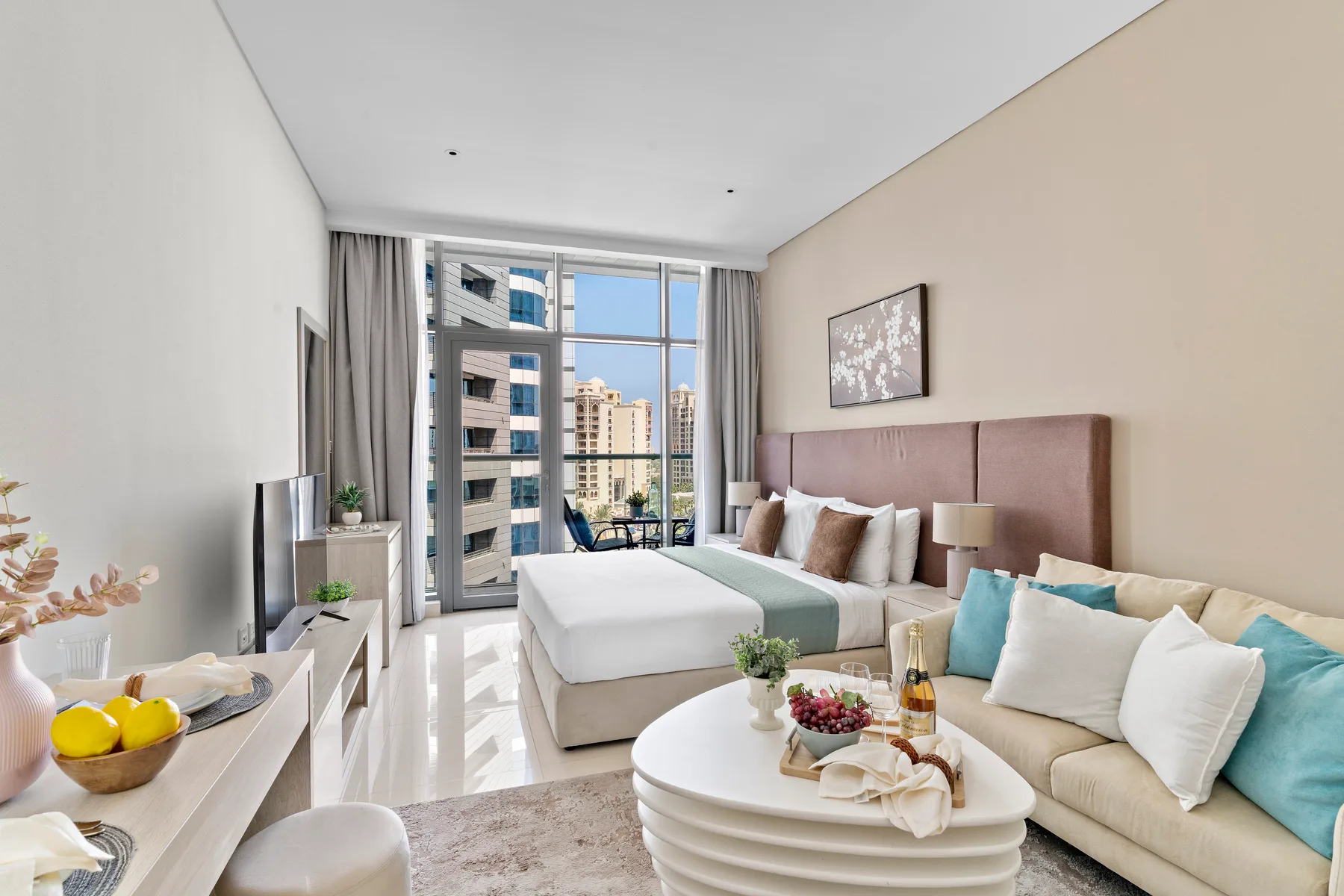 A bright bedroom with a sitting area beside large windows.
