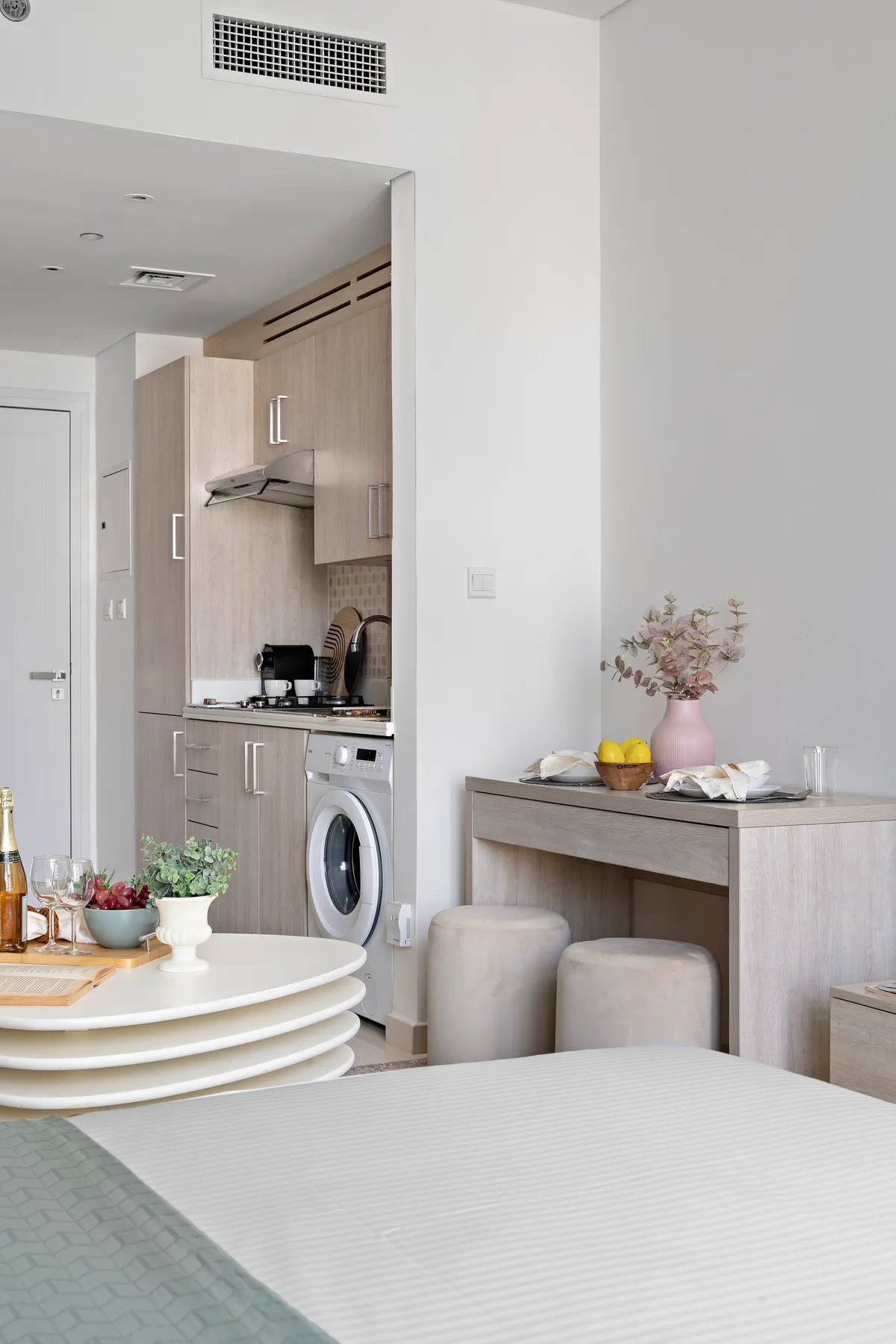 Un estudio luminoso con cocina compacta, mesa de comedor y cama.