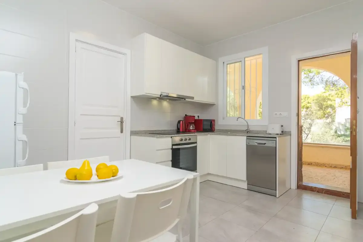 A bright kitchen with white cabinets, appliances, and a dining table.