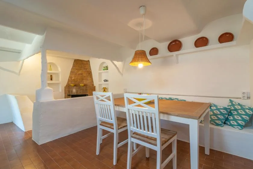 A dining area with a wooden table, white chairs, and a built-in bench.