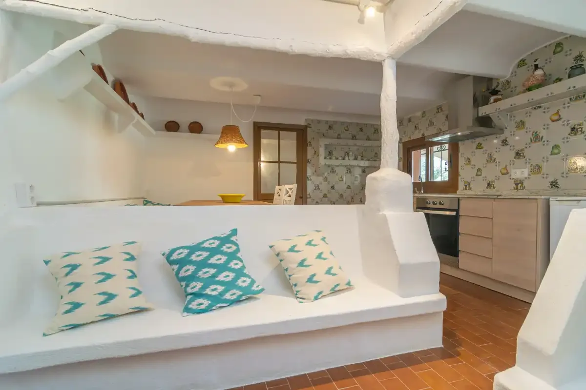 A bright kitchen and dining area with a white built-in bench and patterned cushions.