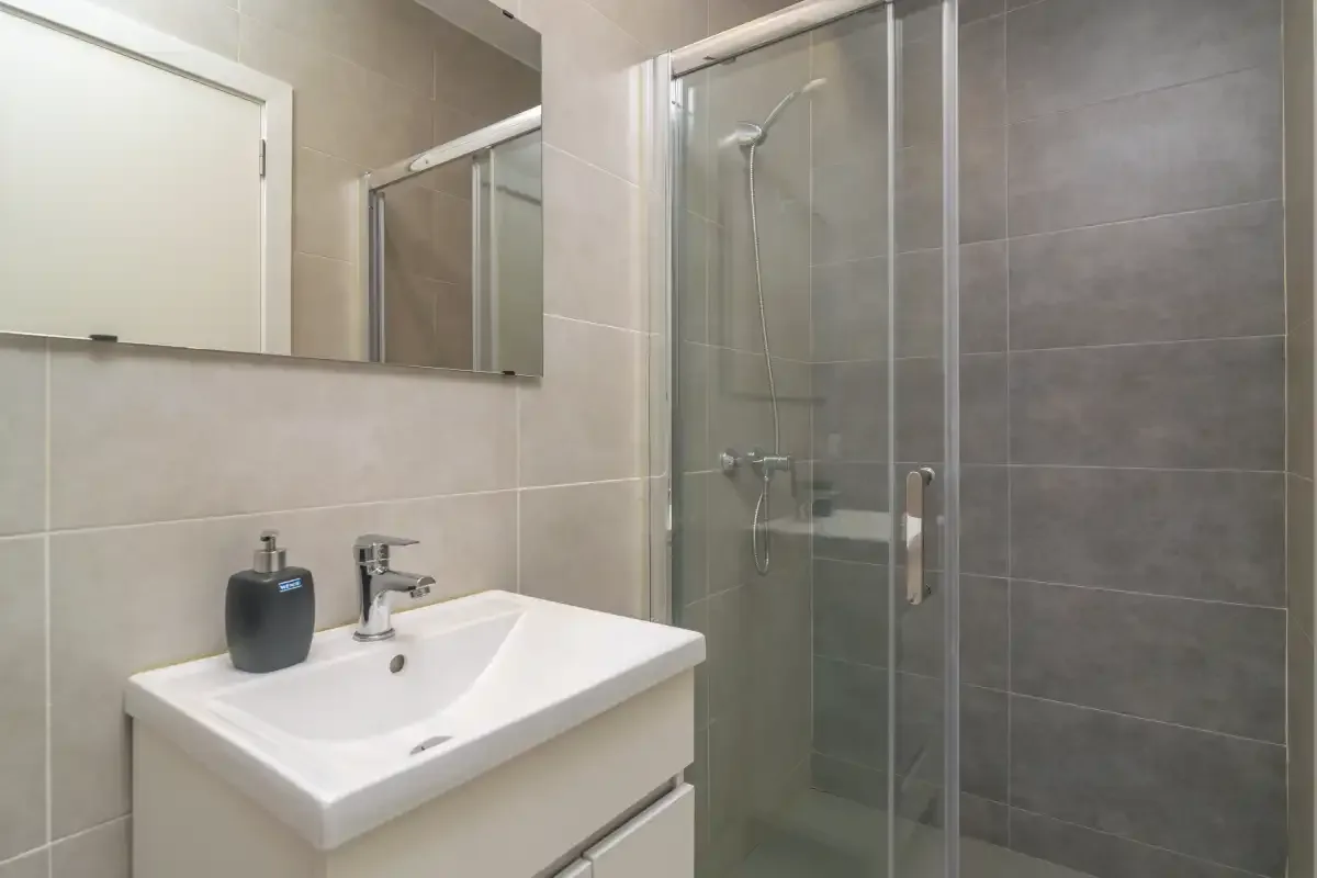 A bathroom with a sink, mirror, and glass shower.