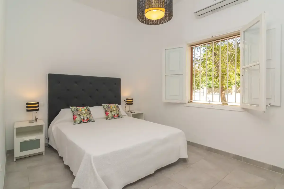 A bright bedroom with a double bed and an open window.