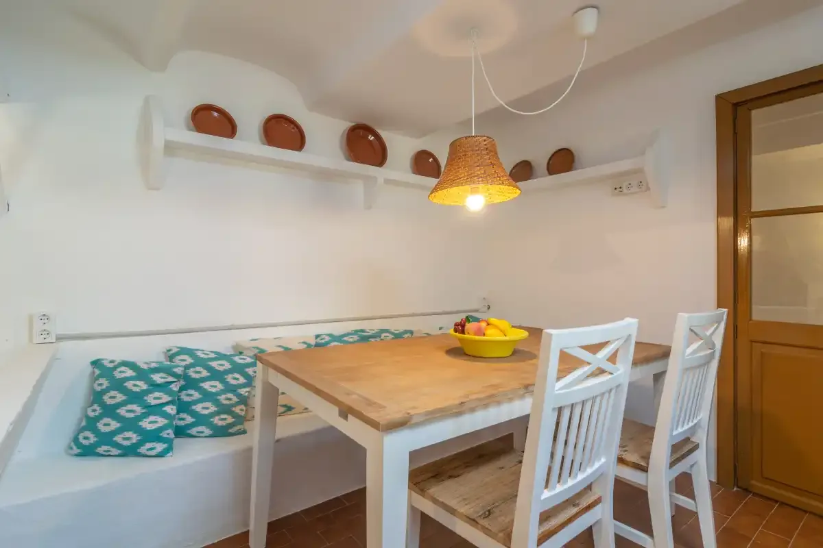 A dining area with a wooden table, white chairs, and a built-in bench.