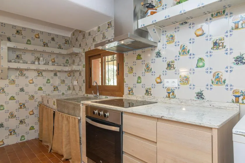 A kitchen with a long countertop, built-in oven, and patterned wall tiles.
