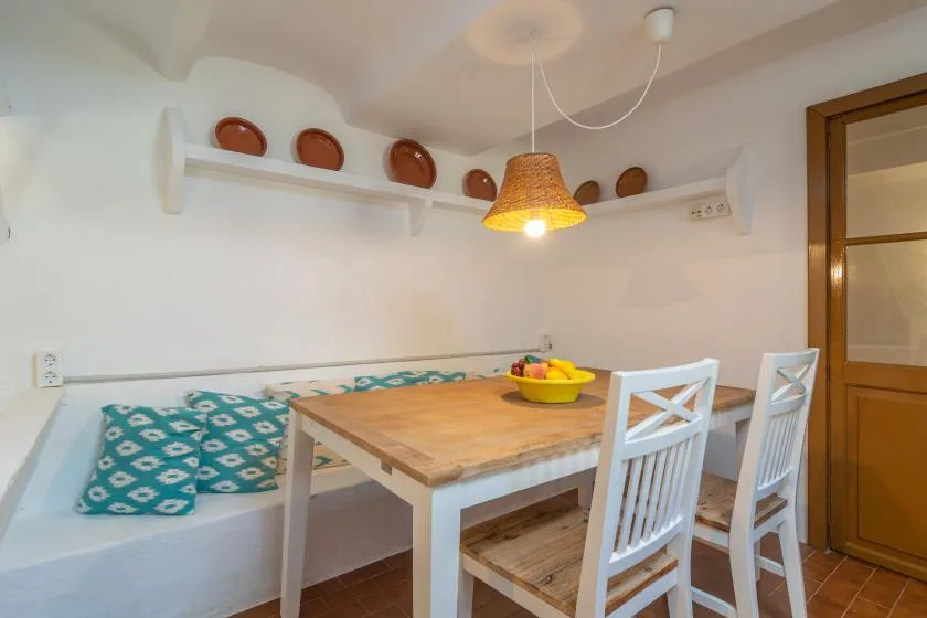 A dining nook with a wooden table, white chairs, and a built-in bench.