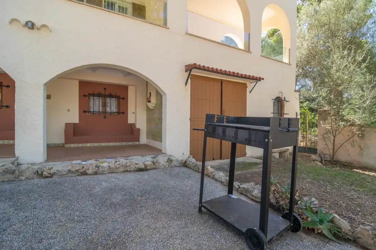 A patio with a built-in bench, wooden doors, and a barbecue grill.