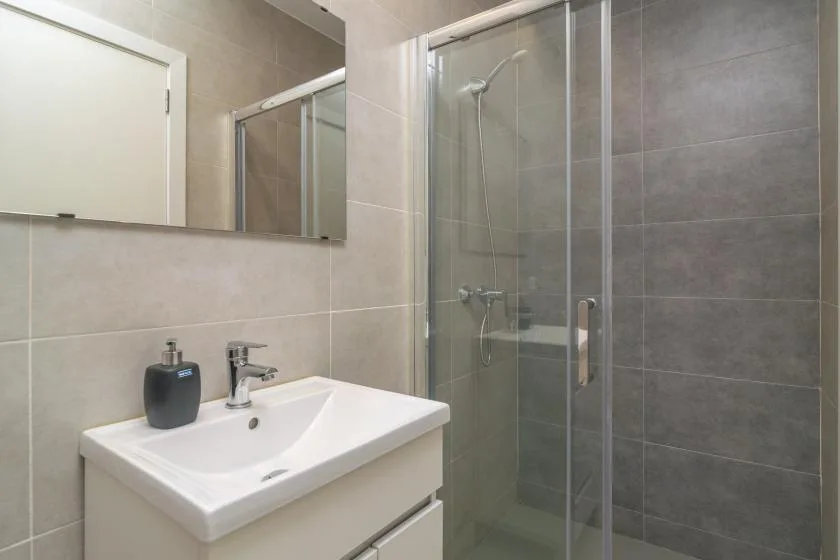 A tiled bathroom with a sink and glass-enclosed shower.