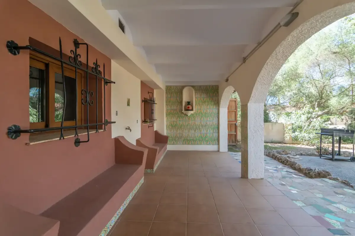 A covered patio with arched openings and a tiled floor.