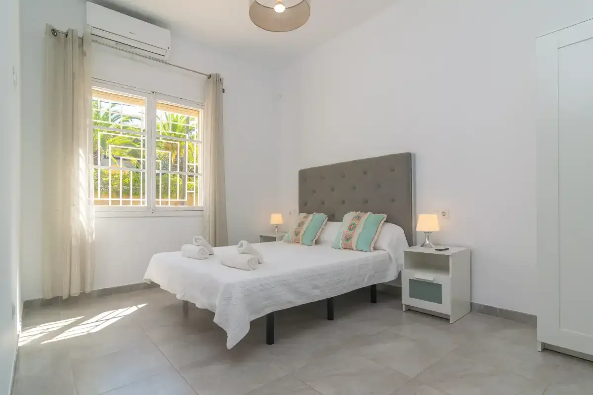 A bright bedroom with a bed and a window.