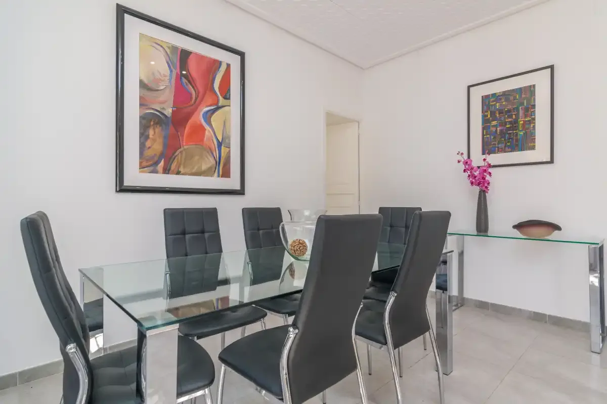 A dining area with glass tables and dark upholstered seating.