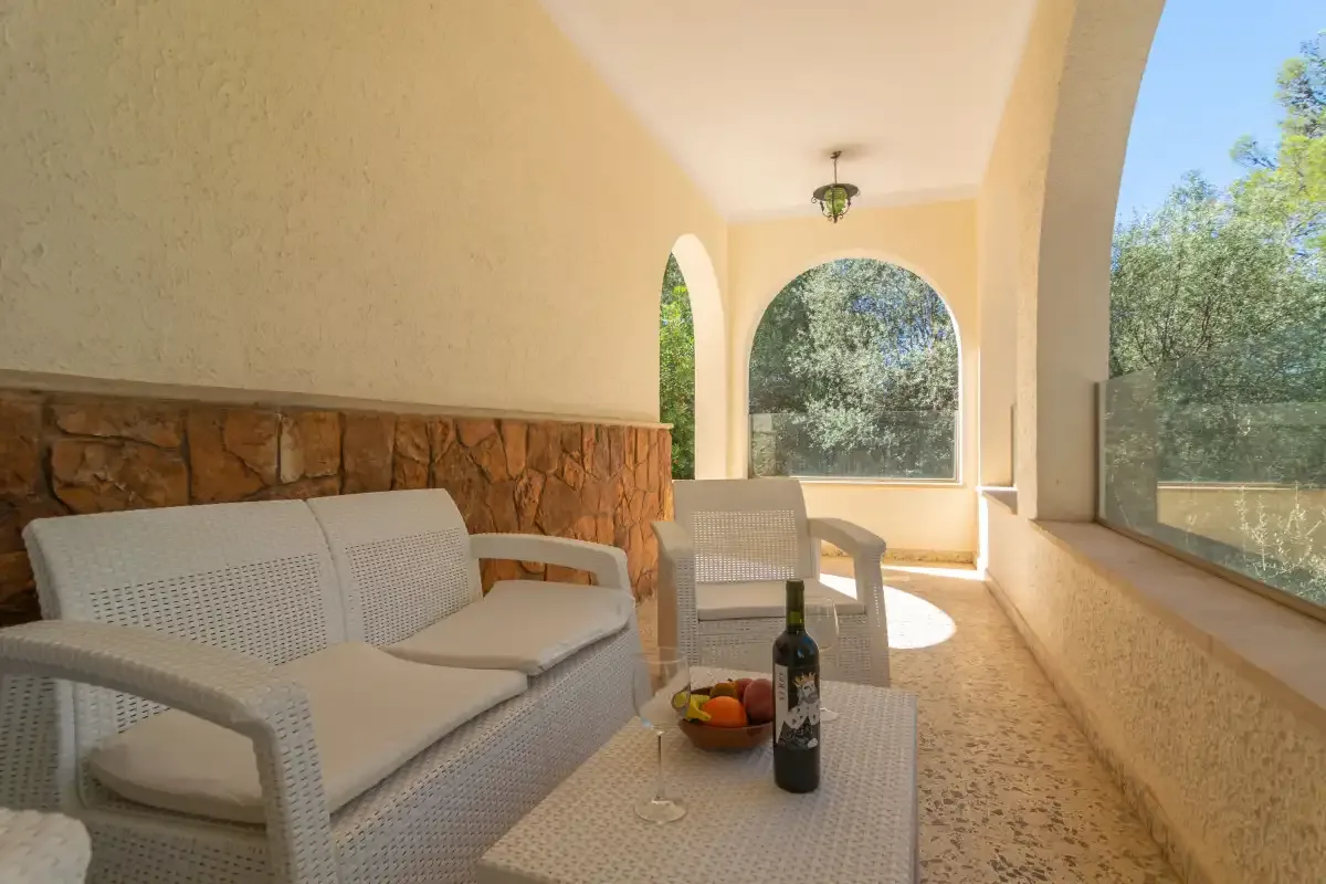 A bright covered patio with cushioned seating and a low table.