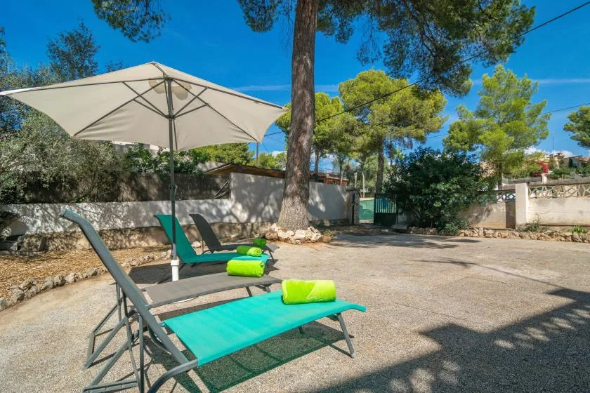 An outdoor patio with turquoise lounge seating beneath a large umbrella.