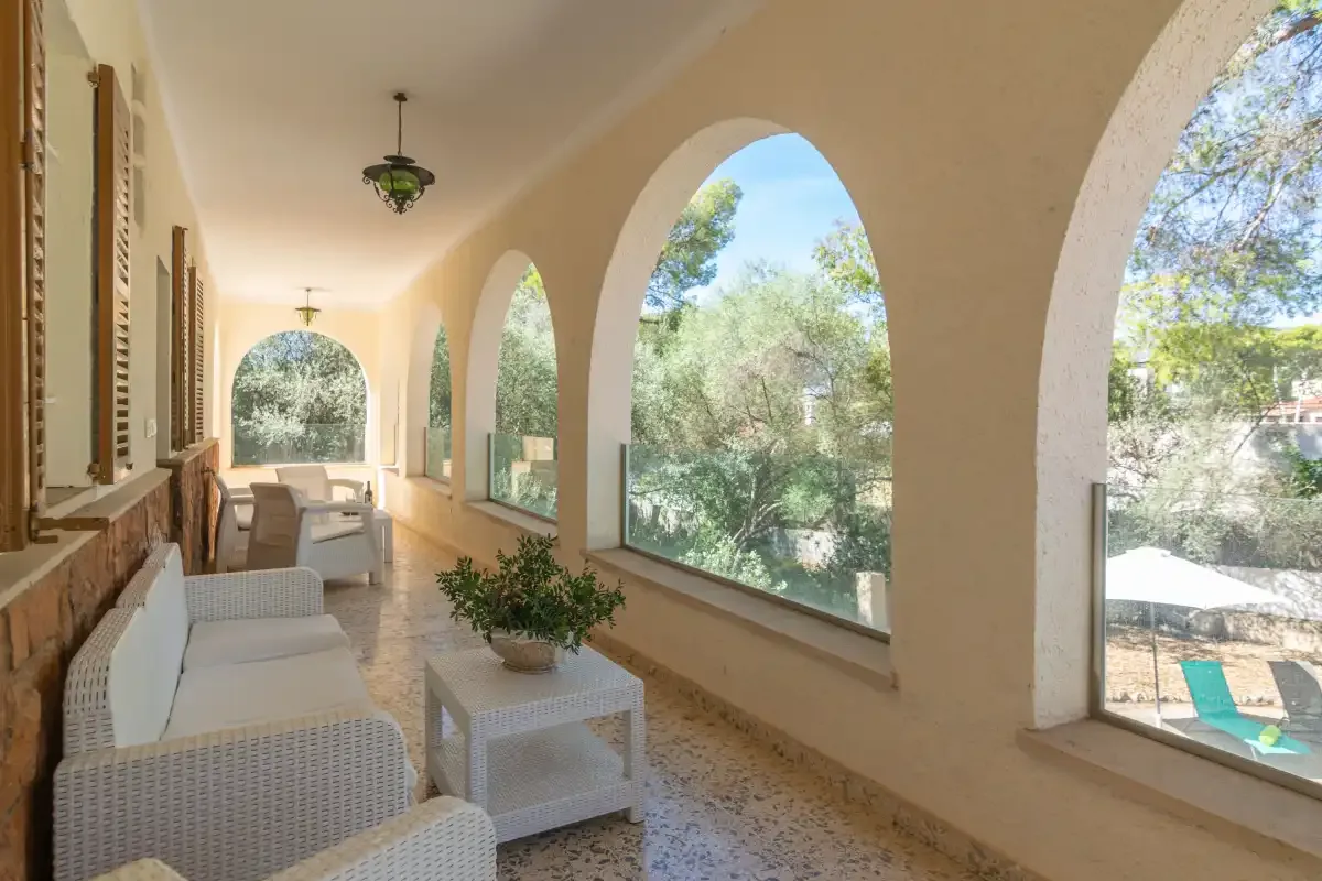 A covered veranda with arched windows and outdoor seating.