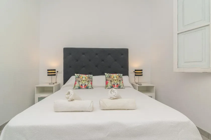 A bedroom with a neatly made bed, colorful pillows, and bedside lamps.