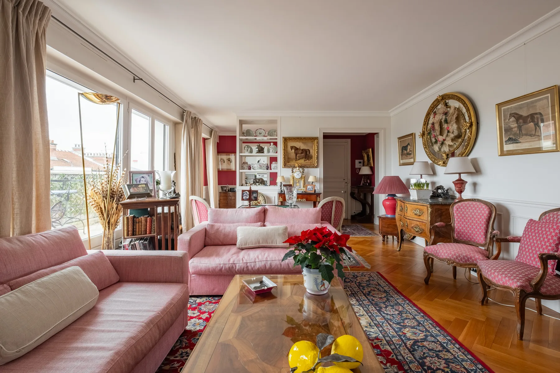 A bright living room with pink seating, a wooden coffee table, and large windows.