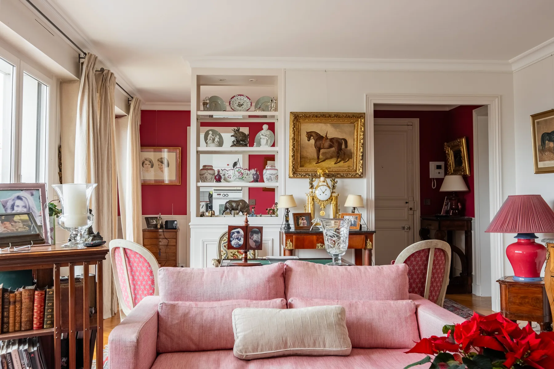 A living room with a pink sofa, display shelves, and framed artwork.