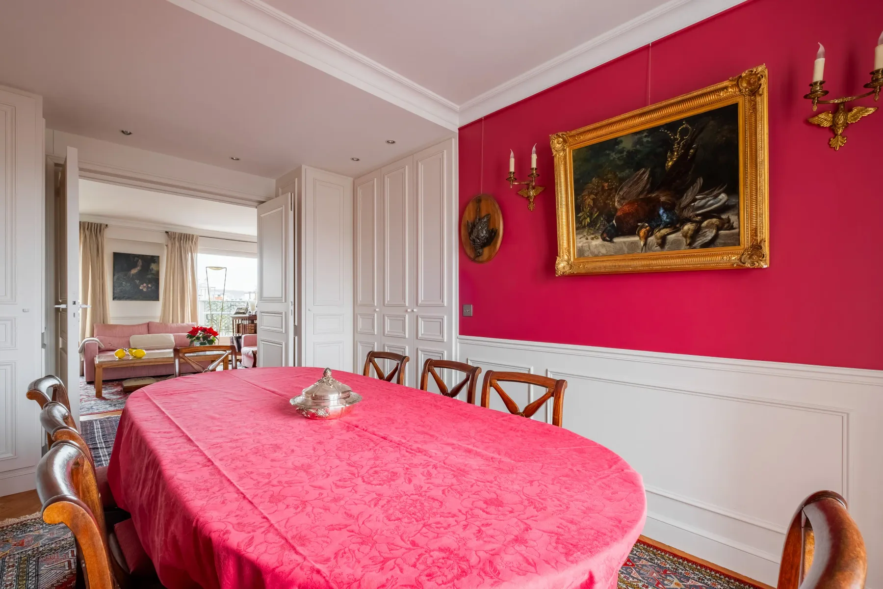 A dining room with a pink tablecloth and a bright pink accent wall.
