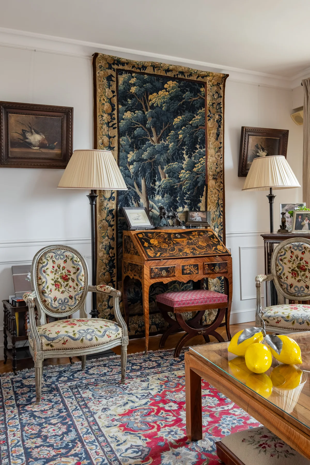 An ornate sitting room features a decorative writing desk and patterned chairs.