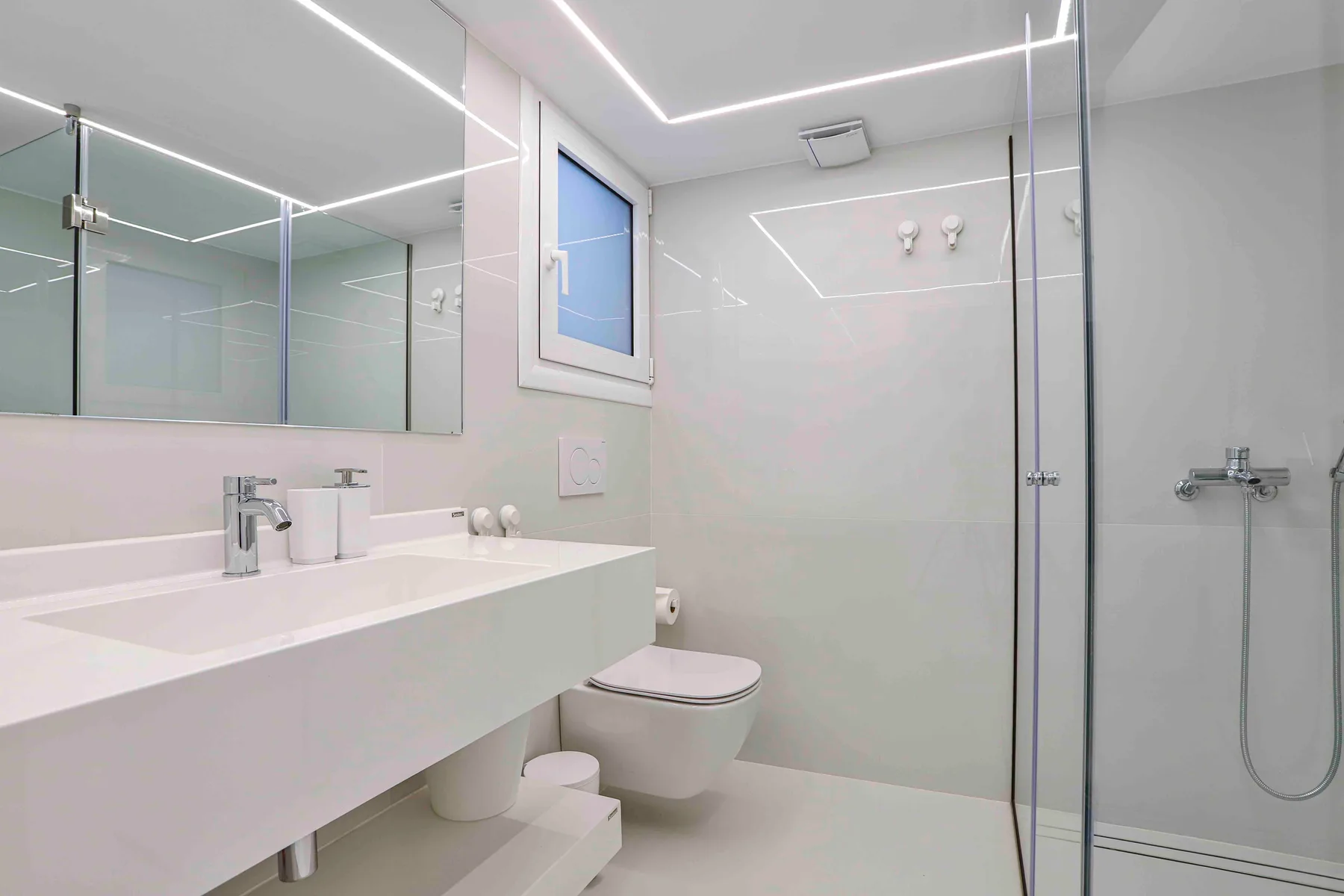 Un baño moderno y luminoso con lavabo suspendido y ducha.
