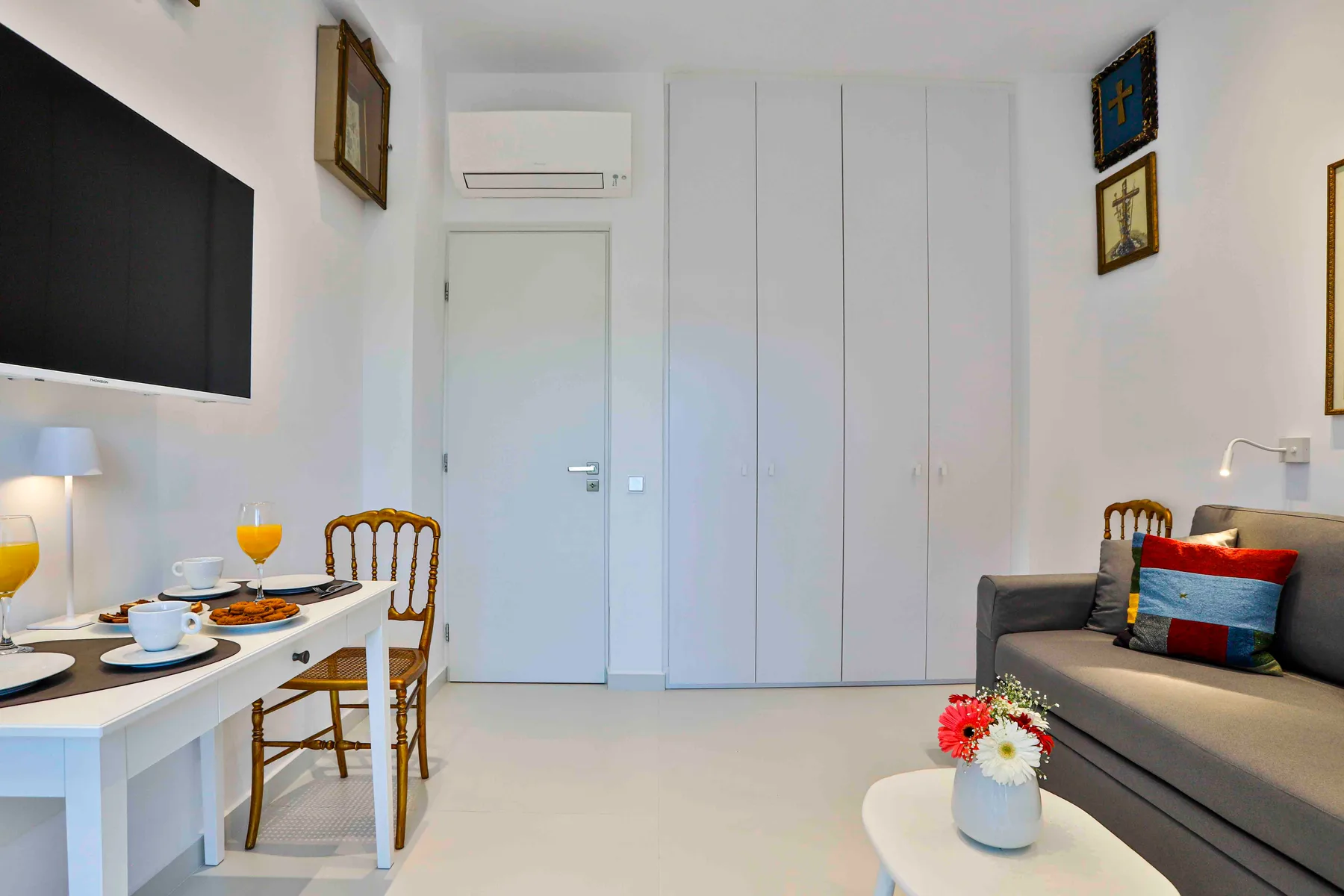 A compact living area with a dining table, seating, and a wall-mounted television.